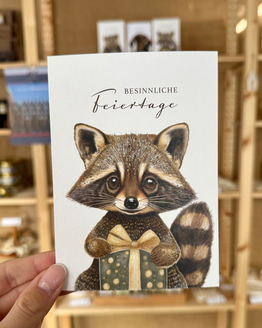 Weihnachten: Postkarte „Waschbär mit Geschenk“